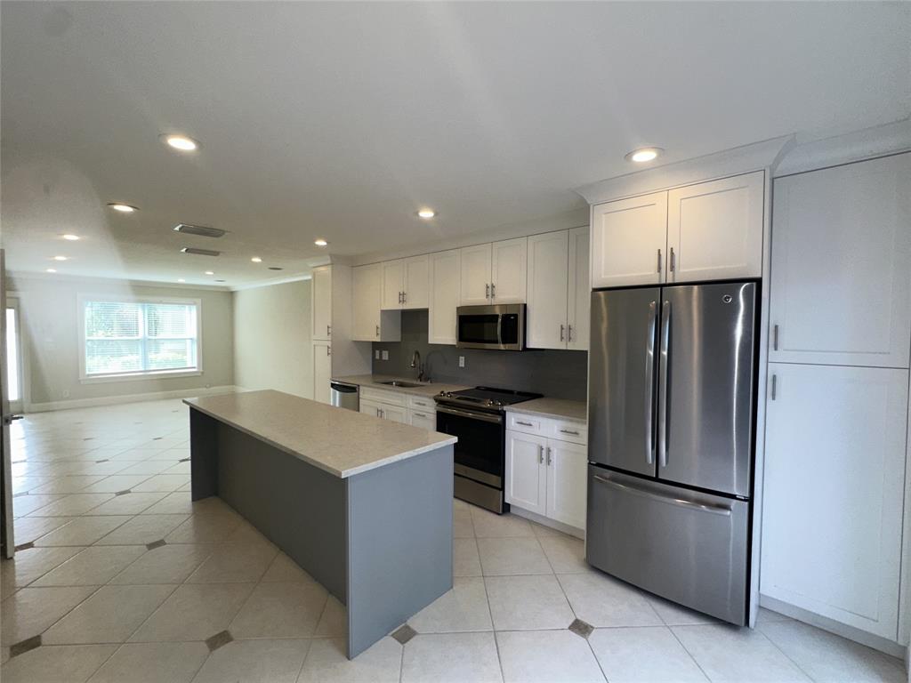 1917 Northeast 3rd Street, Unit 113 Deerfield Beach, FL 33441 - Photo 7 of 23 a kitchen with stainless steel appliances kitchen island a refrigerator sink and stove