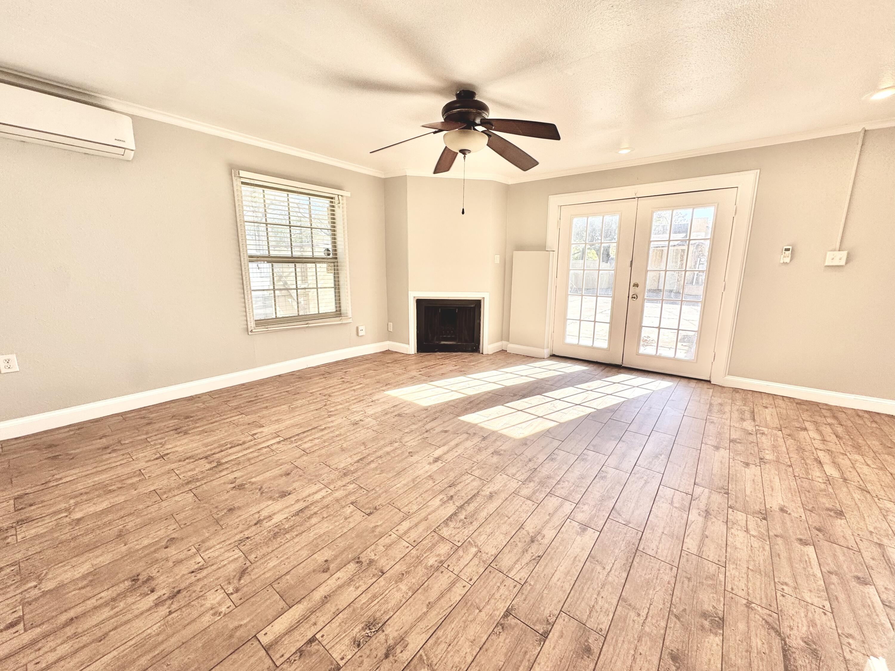 2702 23rd Street, Unit B Lubbock, TX 79410 - Photo 5 of 9 a view of an empty room with wooden floor and a window