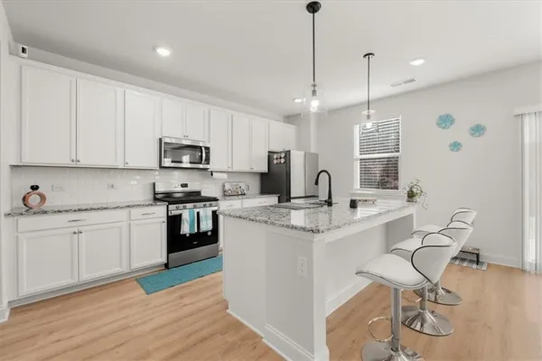 a kitchen with stainless steel appliances granite countertop a sink a stove a refrigerator and island with wooden floor