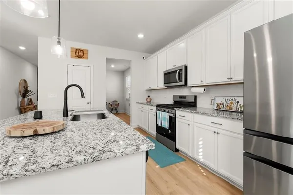 a kitchen with granite countertop a sink stainless steel appliances and white cabinets