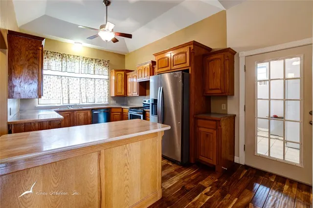 a kitchen with granite countertop a sink cabinets stainless steel appliances and a large window