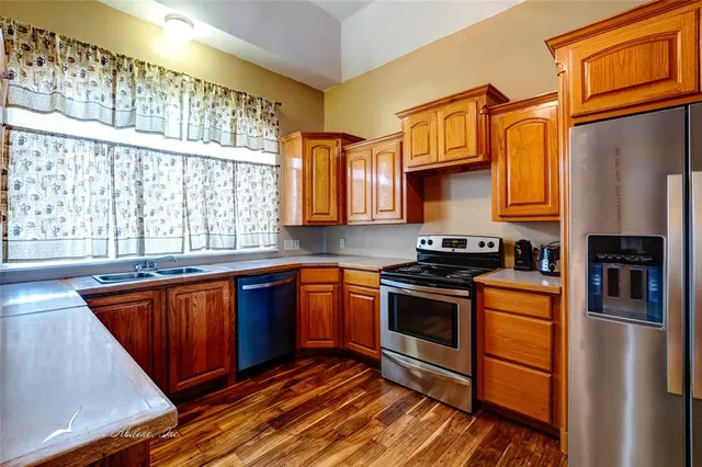 a kitchen with stainless steel appliances a stove a sink and cabinets