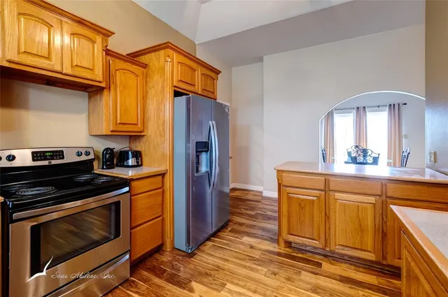 a kitchen with stainless steel appliances granite countertop a sink a stove cabinets and wooden floor