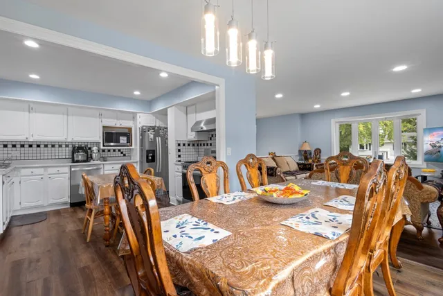 a kitchen with stainless steel appliances kitchen island granite countertop a dining table chairs stove and white cabinets