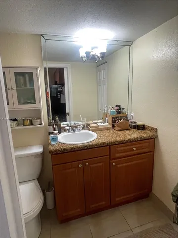 a bathroom with a granite countertop toilet a sink and a mirror