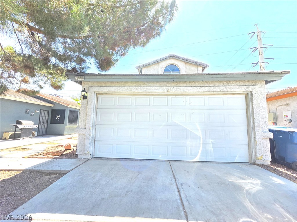 2882 Sandyfalls Way Las Vegas, NV 89142 - Photo 1 of 18 A well-maintained concrete driveway leads to a classic garage with a charming arched window above.