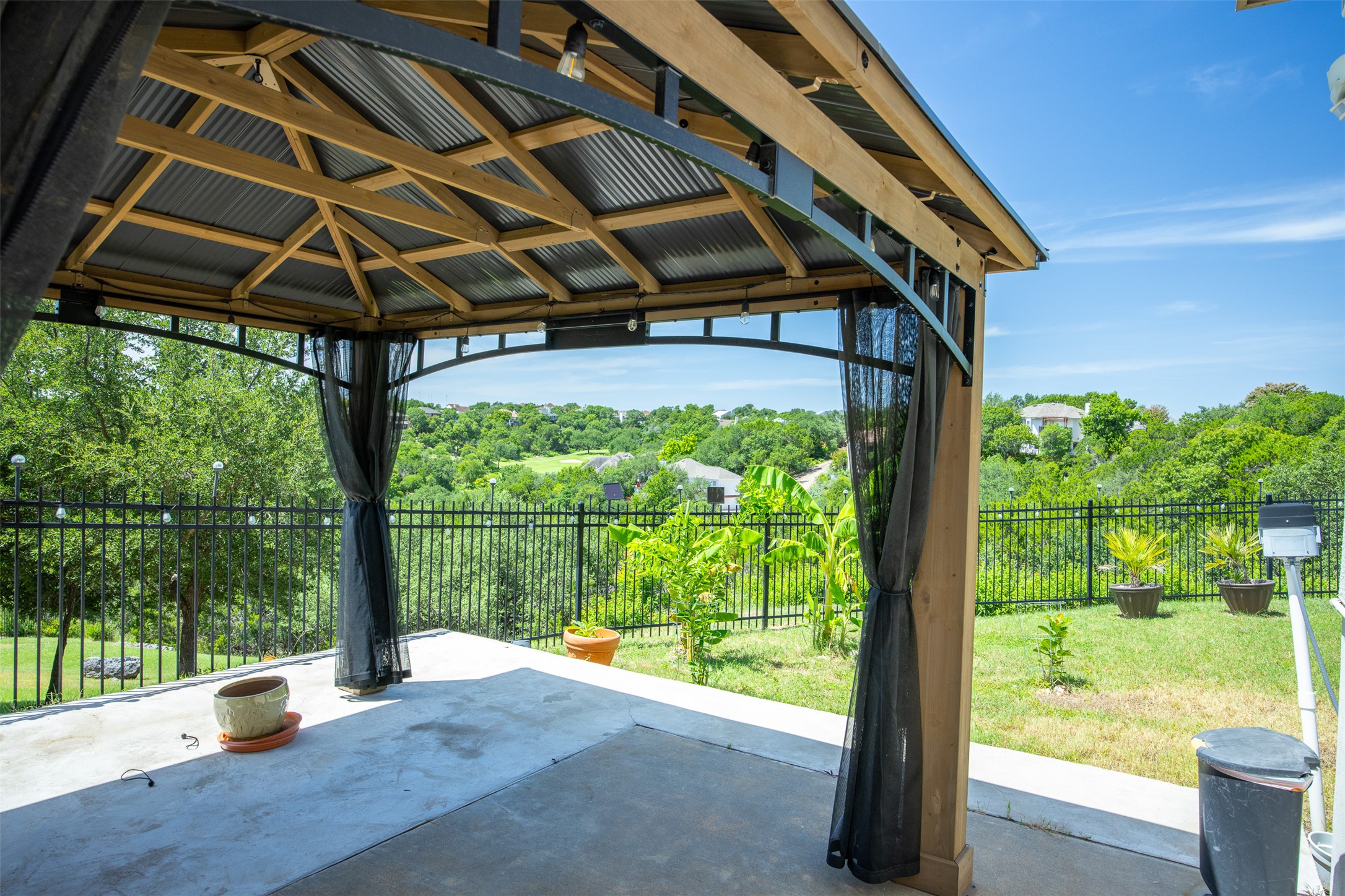 9300 Simmons Road Austin, TX 78759 - Photo 16 of 17 A spacious patio area under a covered gazebo, offering serene views of the surrounding green landscape and distant properties.