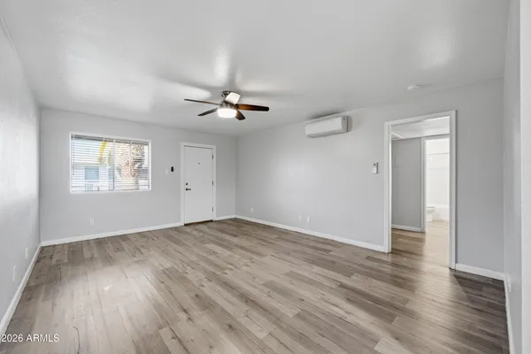 an empty room with wooden floor chandelier fan and windows