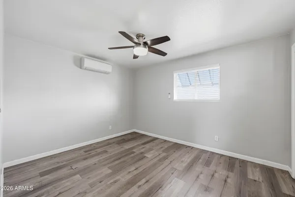 an empty room with wooden floor ceiling fan and windows