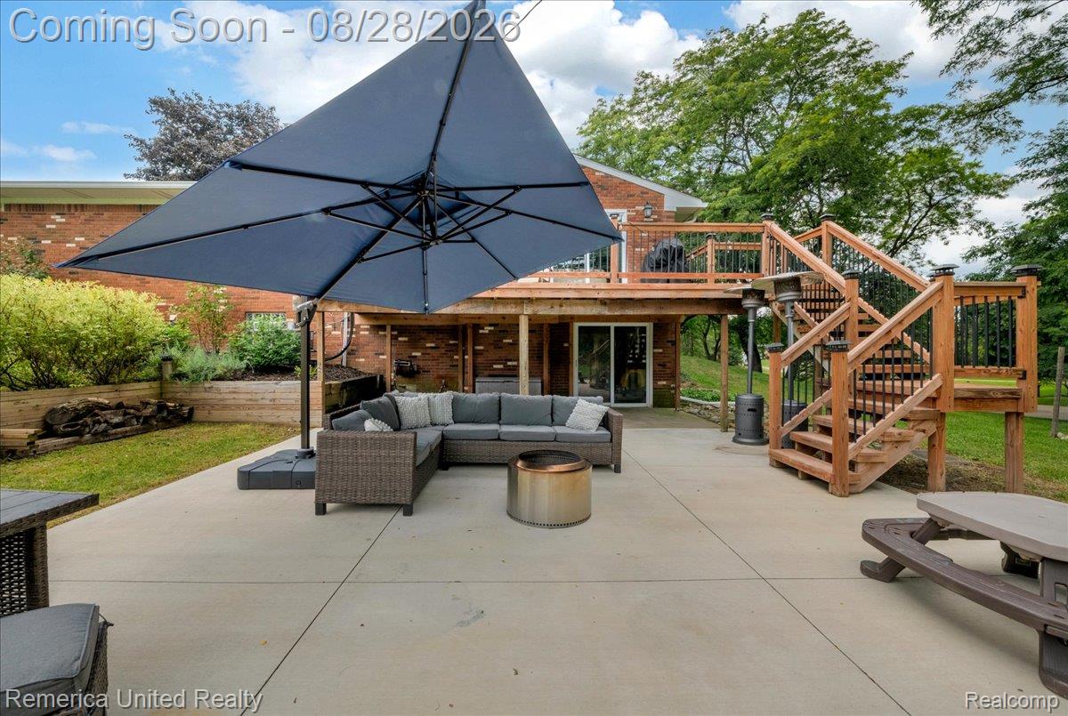 3687 Van Amberg Road Brighton, MI 48114 - Photo 42 of 56 Expansive concrete patio with a multi-level wood deck featuring wood railings and black balusters