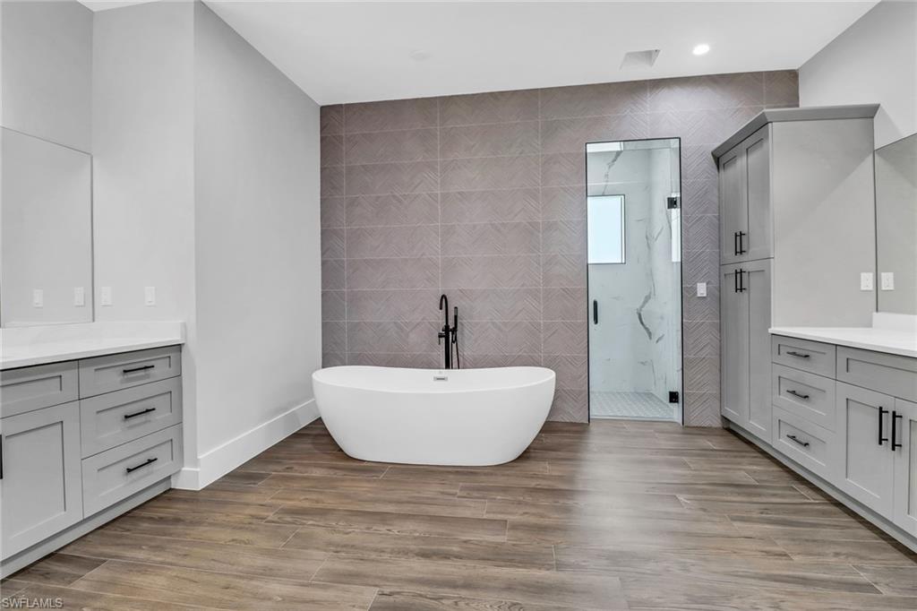 733 15th Street Southwest Naples, FL 34117 - Photo 18 of 34 a spacious bathroom with a double vanity sink a mirror and a bathtub