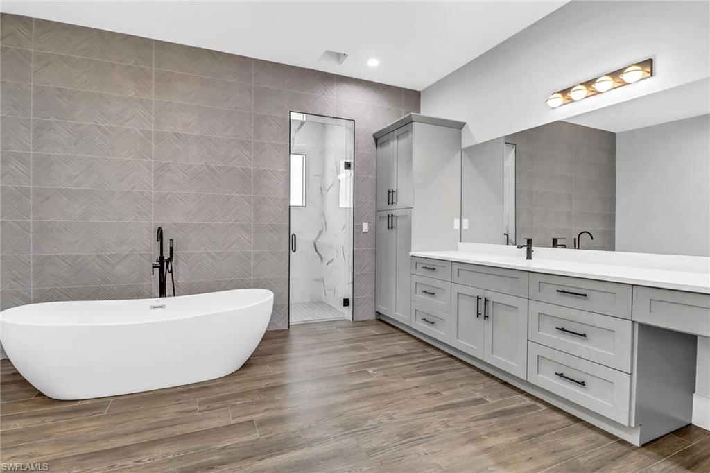733 15th Street Southwest Naples, FL 34117 - Photo 19 of 34 a spacious bathroom with a double vanity sink a mirror and a bathtub