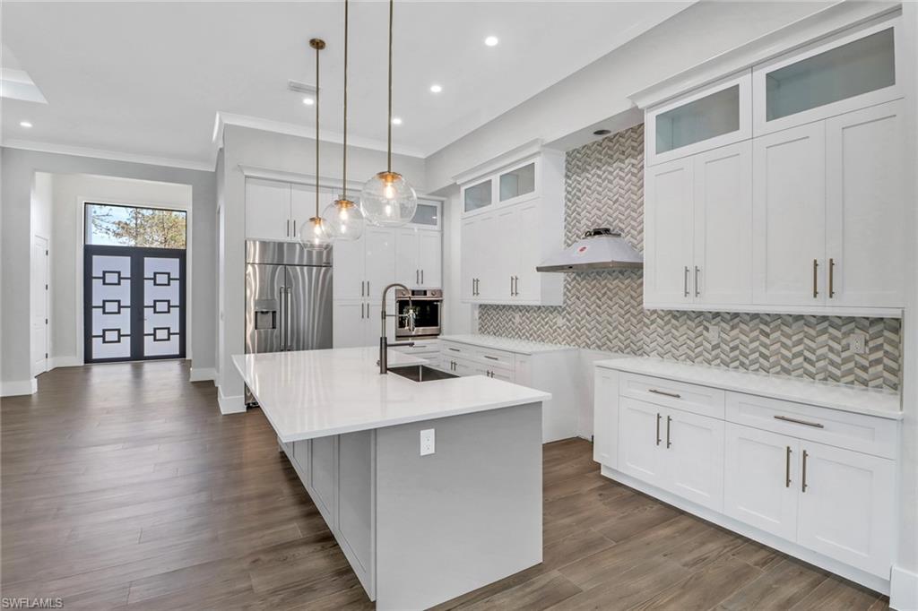 733 15th Street Southwest Naples, FL 34117 - Photo 9 of 34 a kitchen with stainless steel appliances granite countertop a sink a stove and white cabinets with wooden floor
