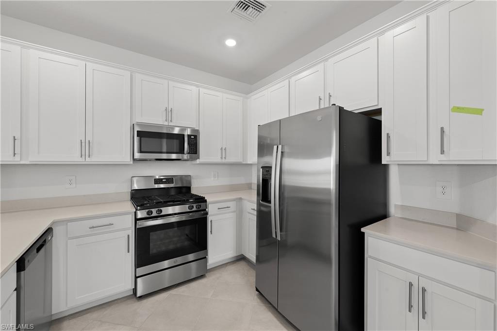 14792 Bluewater Road Babcock Ranch, FL 33982 - Photo 16 of 42 a kitchen with a refrigerator stove and white cabinets