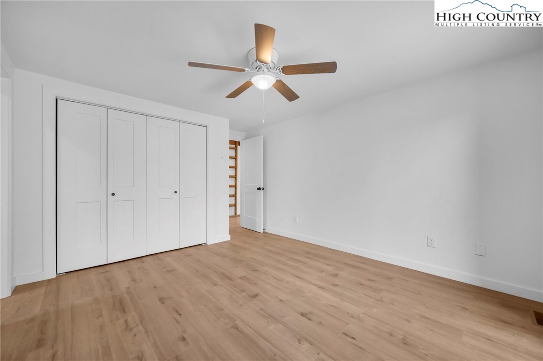 208 Meadow Loop Newland, NC 28657 - Photo 12 of 46 an empty room with wooden floor ceiling fan and windows
