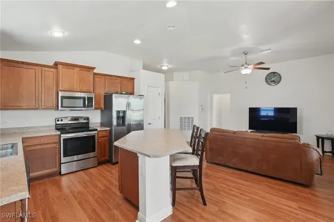 a large kitchen with stainless steel appliances a stove a refrigerator a oven a sink with a dining table and chairs