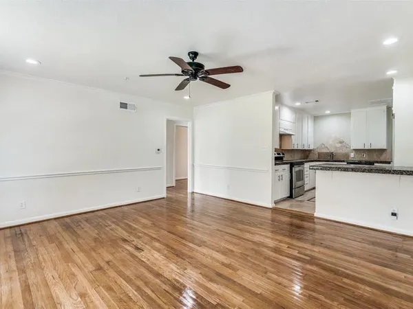 a view of an empty room with kitchen appliances and a ceiling fan