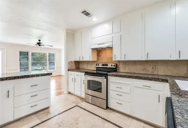a kitchen with granite countertop white cabinets and white appliances
