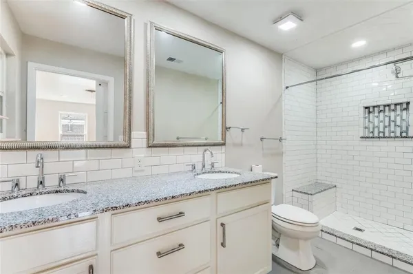 a bathroom with a granite countertop sink a toilet and a mirror