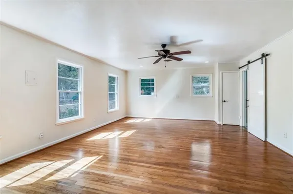 a view of an empty room with window and wooden floor