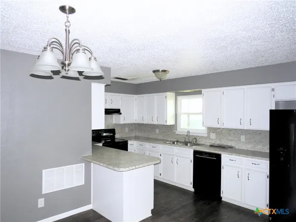 a kitchen with granite countertop white cabinets and stainless steel appliances