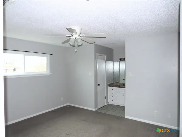 an empty room with windows and fan