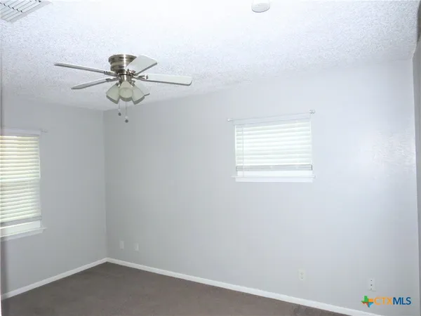 an empty room with a window and a fan