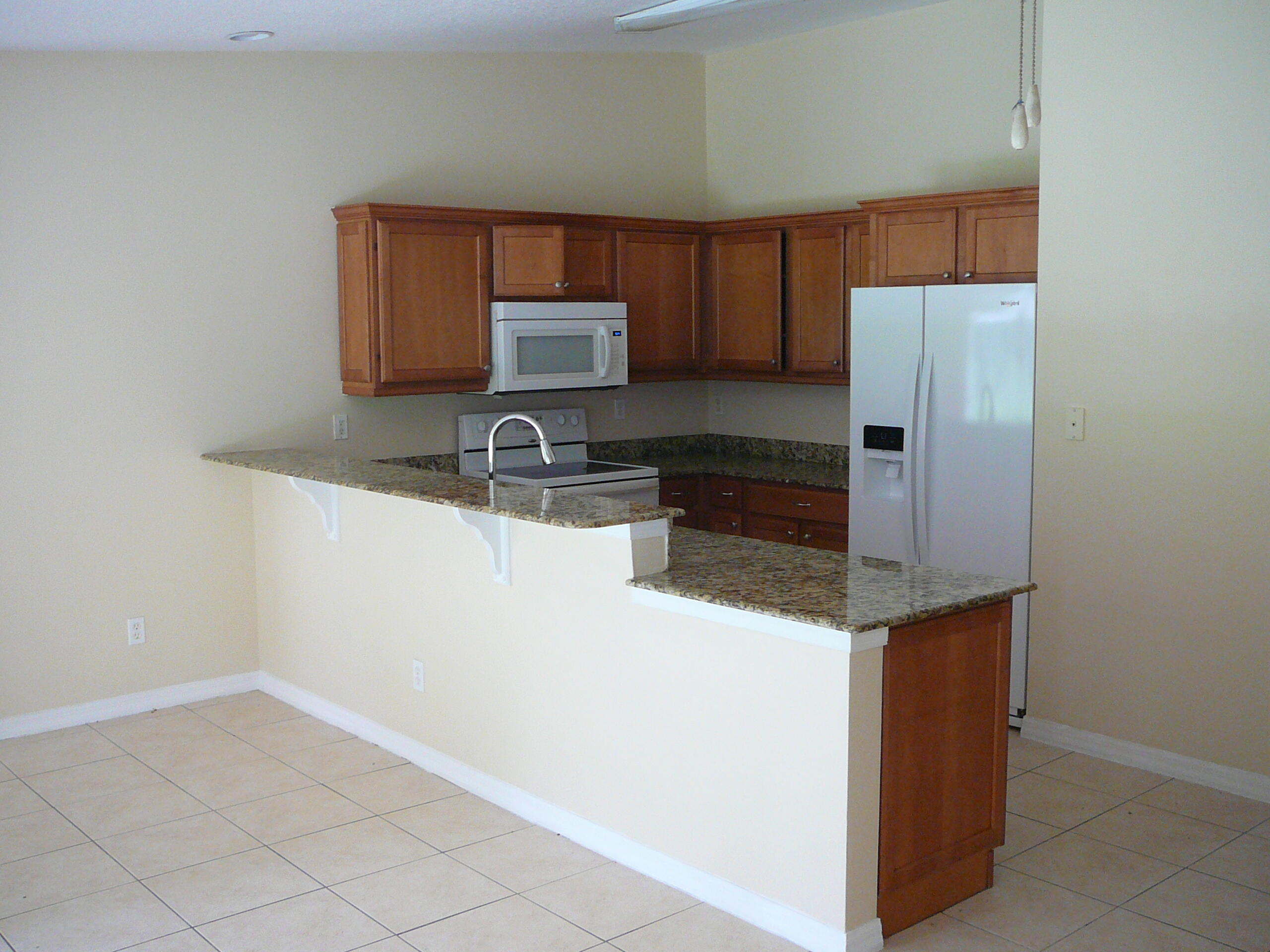 6512 Las Palmas Way Port St. Lucie, FL 34952 - Photo 17 of 45 a kitchen with stainless steel appliances a refrigerator and a stove top oven