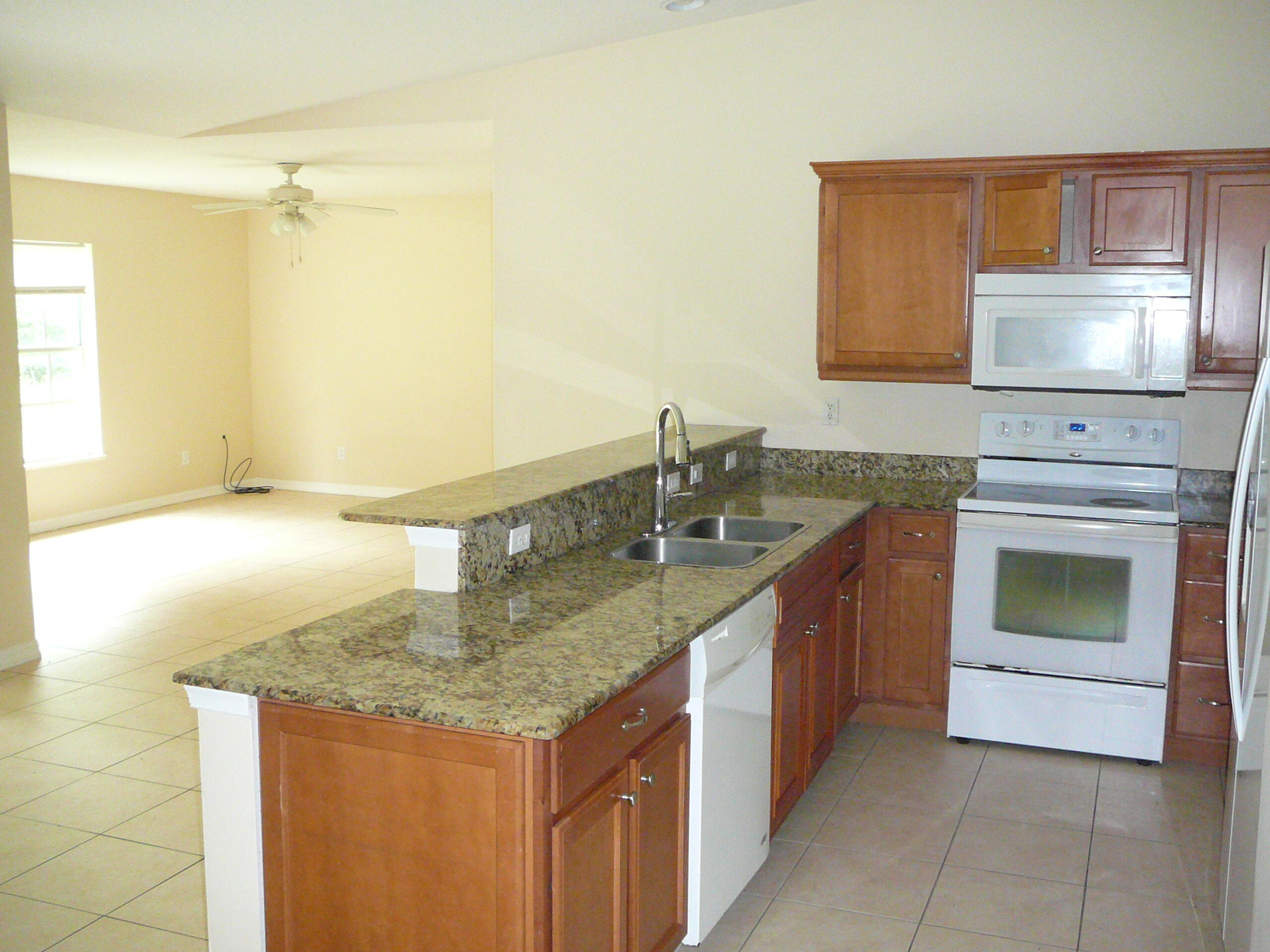 6512 Las Palmas Way Port St. Lucie, FL 34952 - Photo 18 of 45 a kitchen with stainless steel appliances granite countertop a sink and a stove
