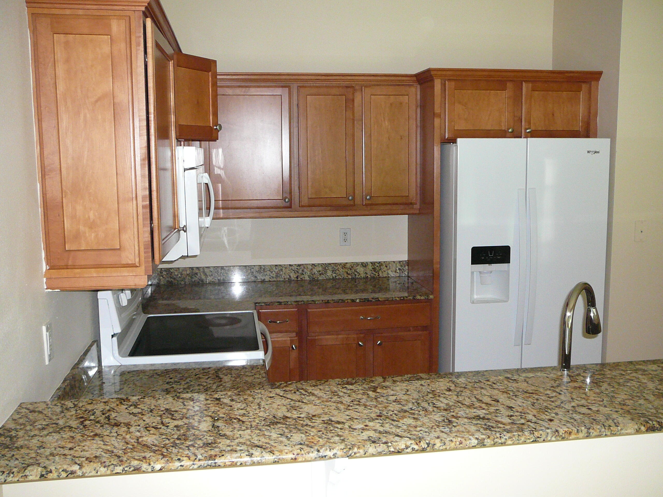6512 Las Palmas Way Port St. Lucie, FL 34952 - Photo 25 of 45 a kitchen with kitchen island granite countertop a refrigerator and a sink