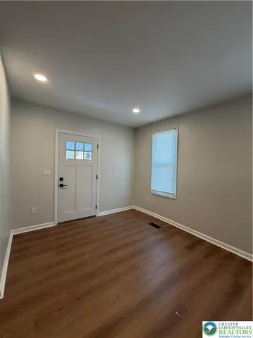 a view of an empty room with window and wooden floor