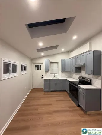 a large kitchen with kitchen island a sink dishwasher a stove a refrigerator and white cabinets with wooden floor