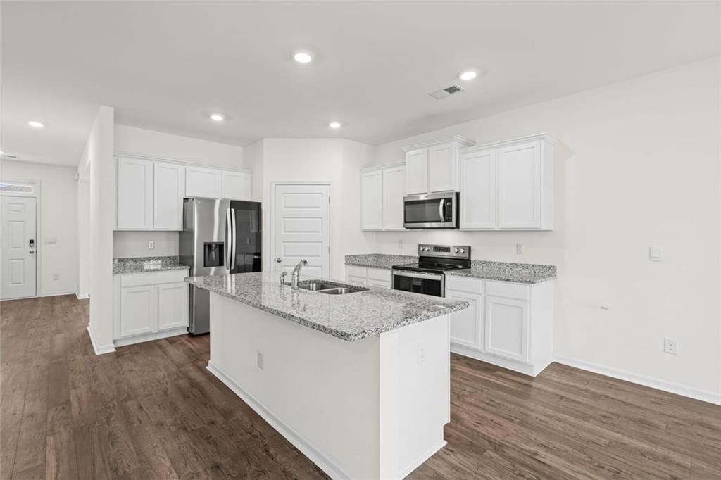 166 Champlain Road Hoschton, GA 30548 - Photo 11 of 53 a kitchen with white cabinets and stainless steel appliances