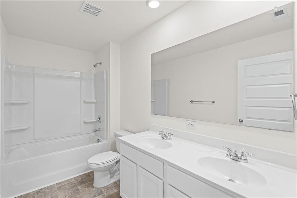 166 Champlain Road Hoschton, GA 30548 - Photo 32 of 53 a bathroom with a toilet a sink a mirror a bathtub and vanity