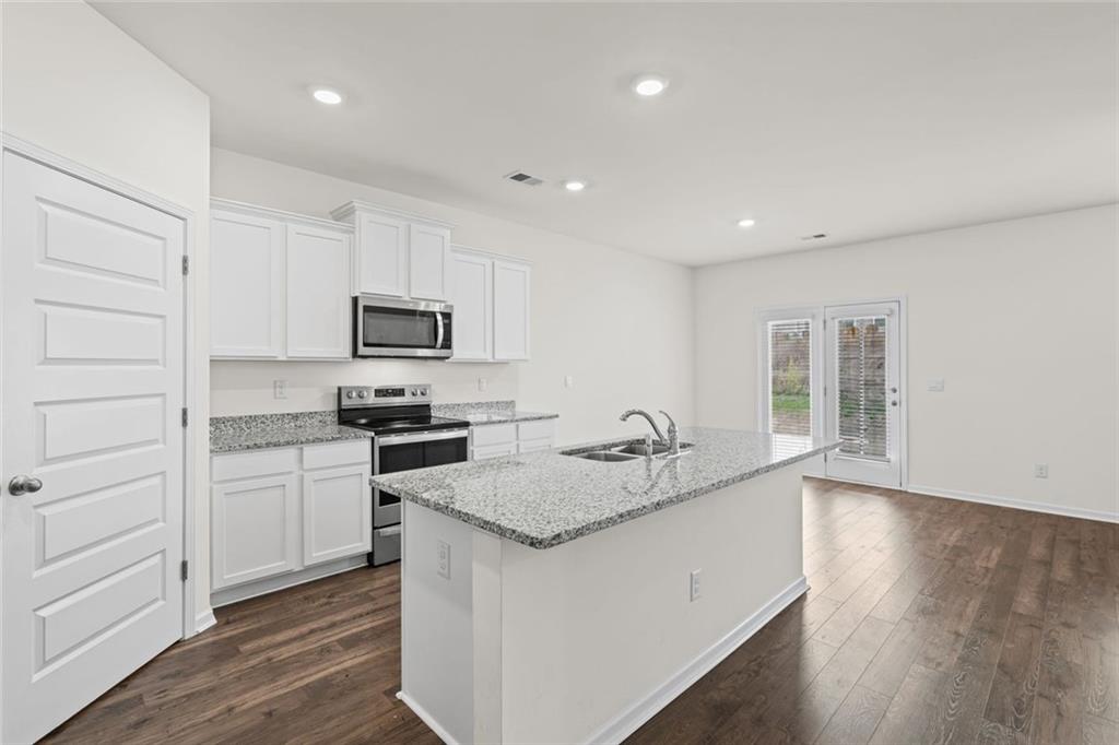 166 Champlain Road Hoschton, GA 30548 - Photo 9 of 53 a kitchen with granite countertop a sink stove and refrigerator