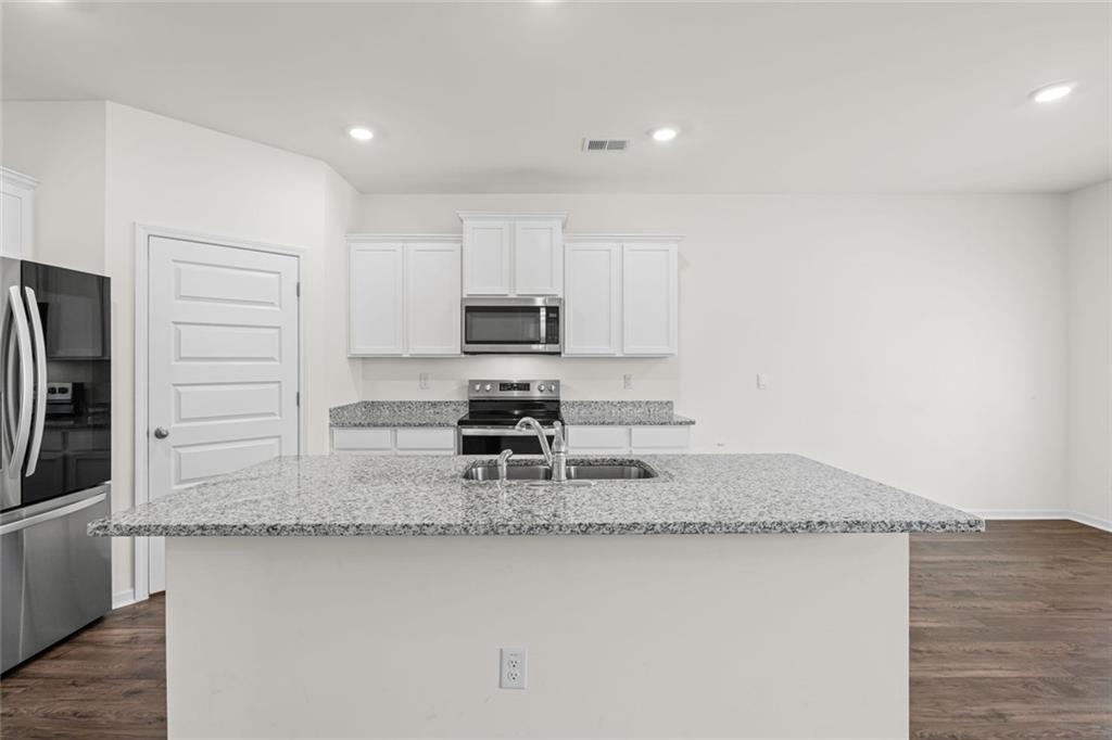 166 Champlain Road Hoschton, GA 30548 - Photo 10 of 53 a kitchen with stainless steel appliances granite countertop a sink a stove a microwave a refrigerator and white cabinets