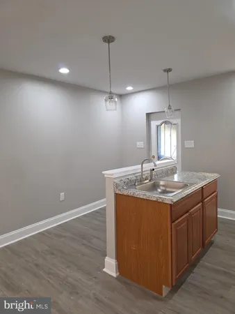 a kitchen with kitchen island stainless steel appliances a dining table chairs sink and wooden floor