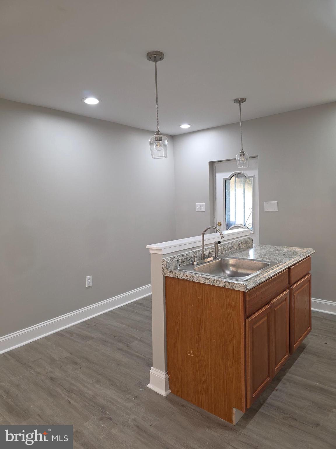 1042 Ellicott Driveway Baltimore, MD 21216 - Photo 4 of 13 a kitchen with kitchen island stainless steel appliances a dining table chairs sink and wooden floor