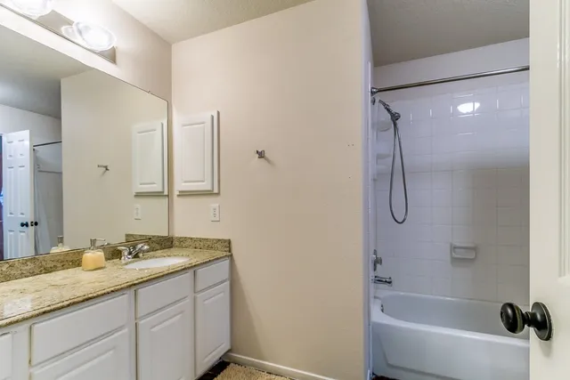 a bathroom with a granite countertop sink a mirror and a bathtub