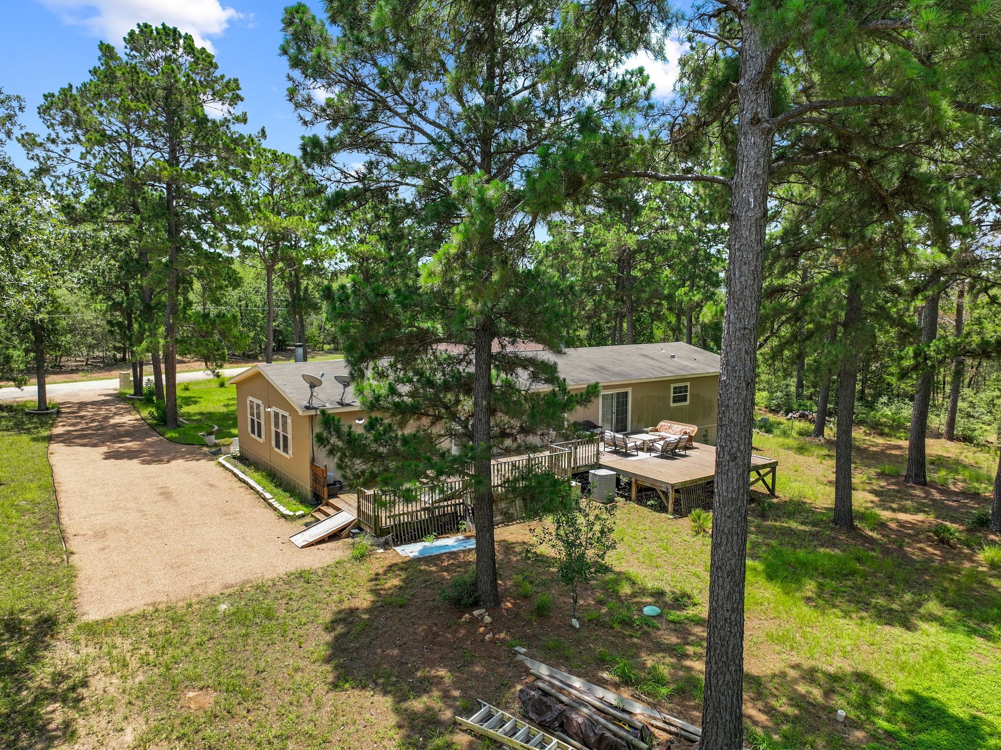 438 Kellar Road Smithville, TX 78957 - Photo 3 of 30 A tranquil wood-sided residence with a broad rear deck, nestled among towering trees.
