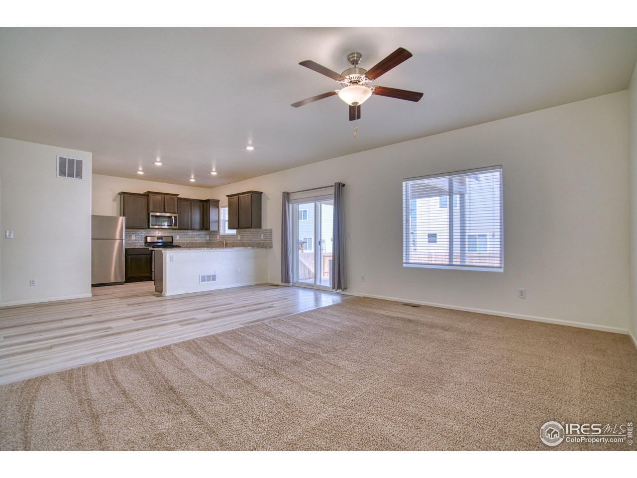 7015 Fall River Drive Frederick, CO 80530 - Photo 11 of 34 a view of kitchen and empty room with wooden floor