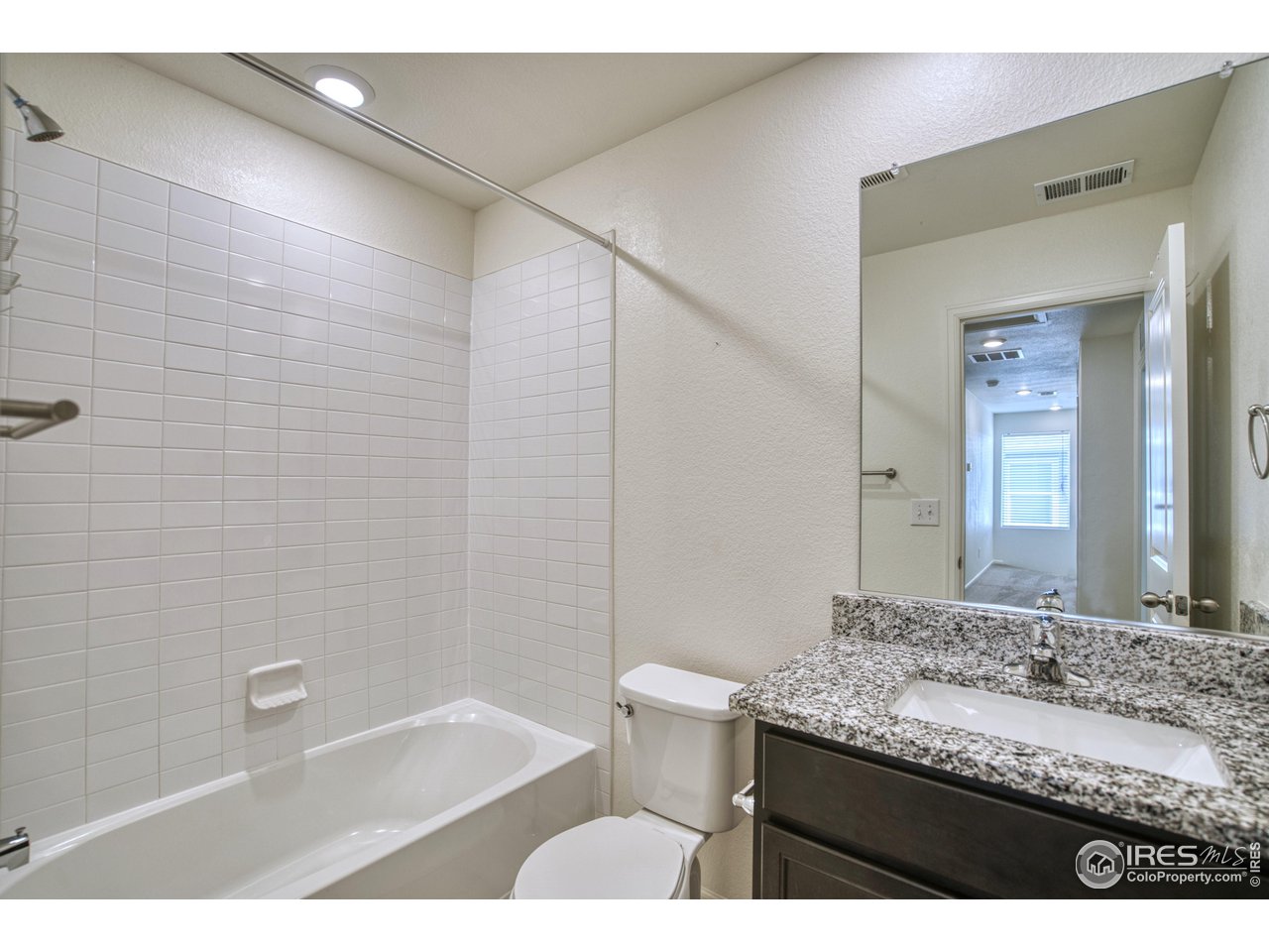 7015 Fall River Drive Frederick, CO 80530 - Photo 23 of 34 a bathroom with a granite countertop sink a toilet and bathtub