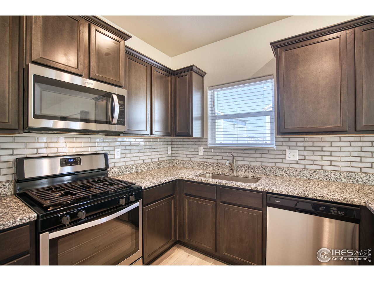 7015 Fall River Drive Frederick, CO 80530 - Photo 6 of 34 a kitchen with granite countertop stainless steel appliances a sink stove and cabinets