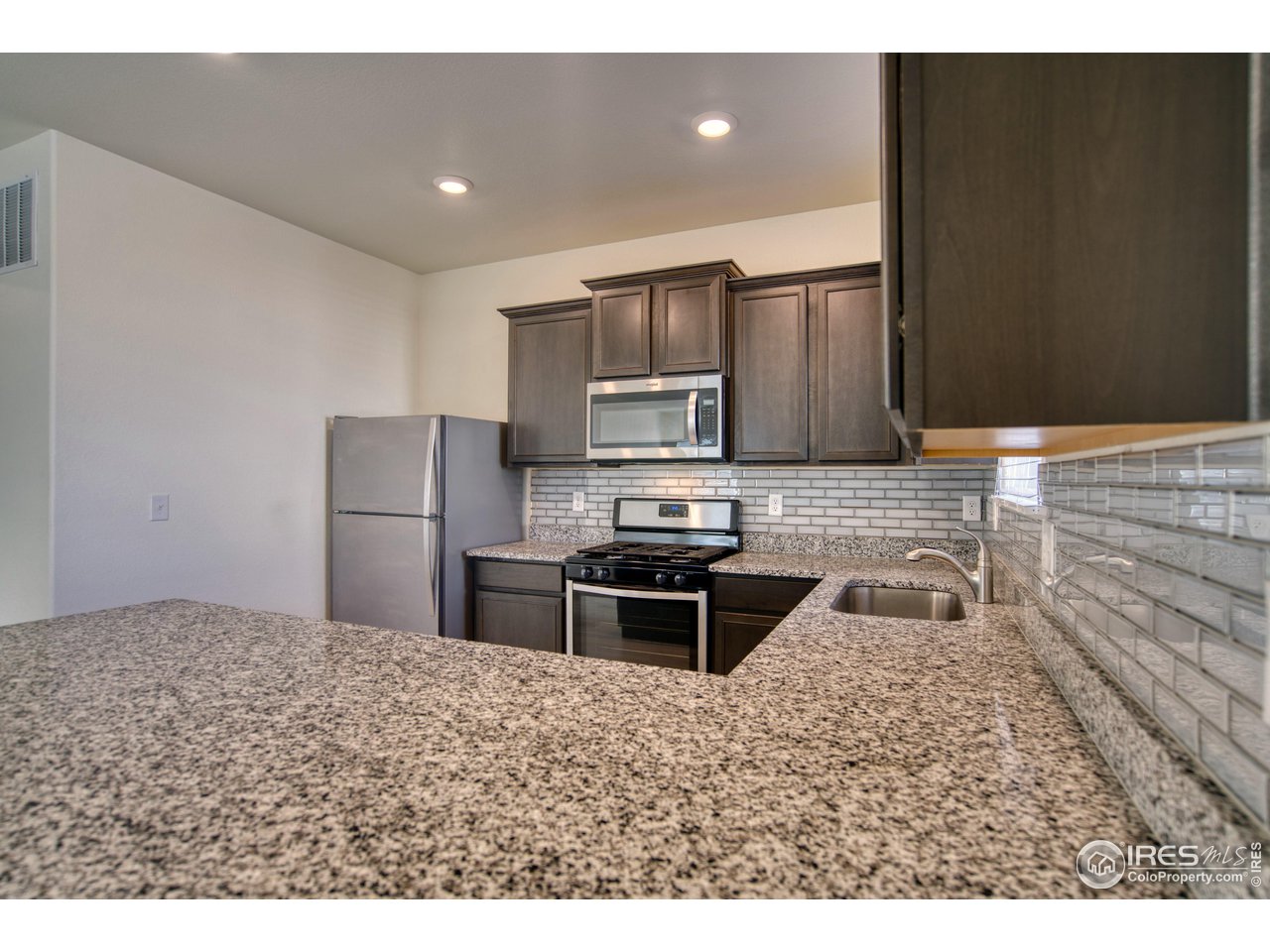 7015 Fall River Drive Frederick, CO 80530 - Photo 9 of 34 a kitchen with kitchen island a counter top a stove a microwave and refrigerator