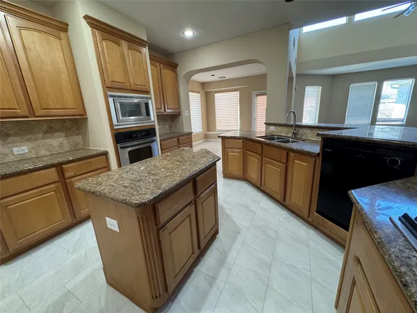 a kitchen with granite countertop refrigerator stove and sink
