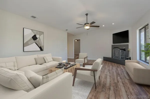 a living room with furniture a ceiling fan and a flat screen tv