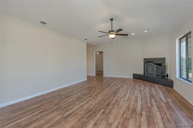 a view of empty room with wooden floor fireplace and fan