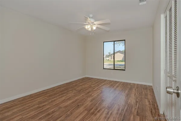 a view of empty room with wooden floor and fan