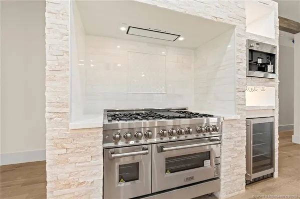 a large kitchen with stainless steel appliances kitchen island granite countertop a large kitchen island a stove a sink a refrigerator and a cabinets with wooden floor