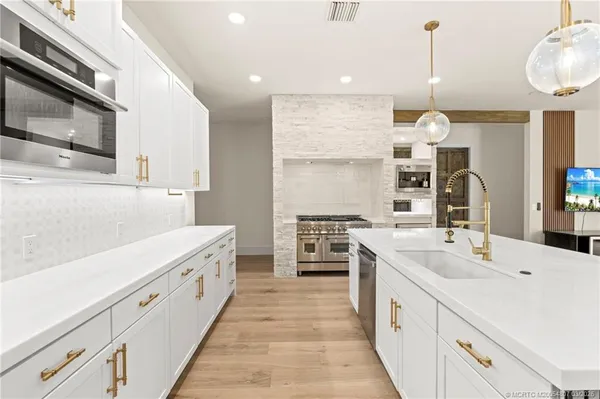 a large kitchen with stainless steel appliances kitchen island granite countertop a large cabinets a sink and a counter top space